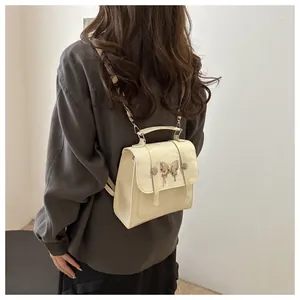 Detail view of cream white PU leather backpack with metallic butterfly and vintage buckles