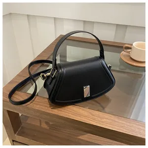 Detail of a chic black semi-circle handbag with silver buckle in an elegant cafe setting