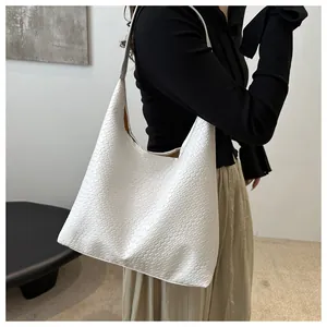 Close-up of white woven hobo bag with wide leather cross-weave texture and long shoulder strap