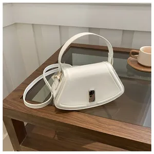Detailed close-up of a white textured crossbody bag with silver buckle on a glass table
