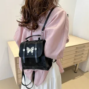 Fashionable black mini backpack with silver butterfly detail on textured material