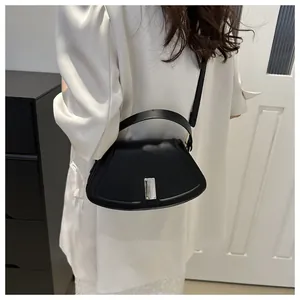 Fashionable black crescent moon crossbody bag with sleek silver buckle on model