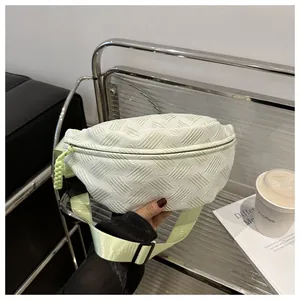 Detail of mint green woven crossbody bag with geometric texture and knotted zipper pull