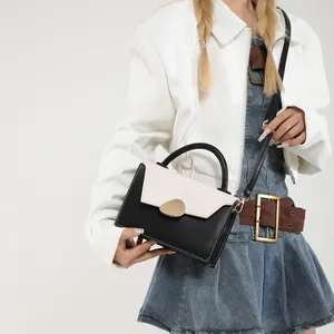 Fashionable black and white contrast handbag with gold clasp shown on a model
