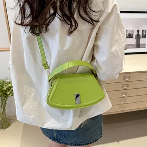 Neon green semicircular crossbody bag with silver buckle worn by a model in casual outfit