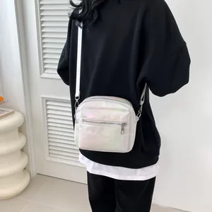Iridescent holographic crossbody square bag with adjustable strap worn by a model