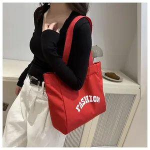 Detailed side view of a red canvas tote bag with white Fashion text worn by a model