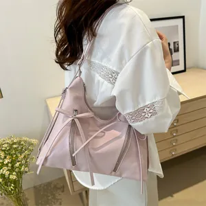 Pink fashion shoulder tote bag with bow ribbon and metal zippers shown on a model