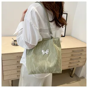 Detail of light green soft tote bag with white 3D butterfly ornament on textured fabric