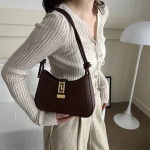 Fashionable dark brown leather underarm baguette bag with elegant golden geometric metal buckle