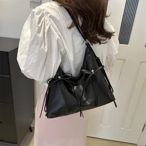 Minimalist black PU leather tote bag with bow detail and zippers worn by a model