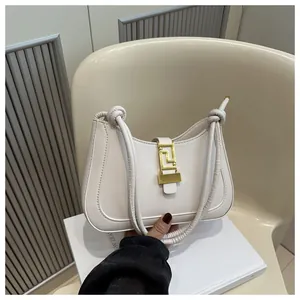 Detail shot of a cream leather shoulder bag with a vintage gold Greek key metal buckle