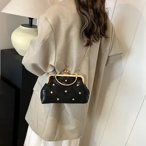 Vintage black shell bag with gold heart studs and metal chain strap shown on model