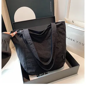 Detail einer schwarzen Nylon-Tragetasche mit Faltentextur in einer Geschenkbox
