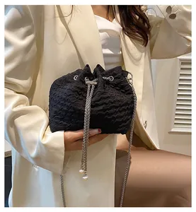 Détail du sac seau plissé noir avec chaîne argentée et breloques en perles blanches