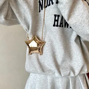 Chic metallic gold star-shaped mini crossbody bag with sleek gold chain strap on model