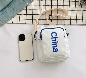 Close-up of a white canvas crossbody bag featuring a blue China print and zipper pockets