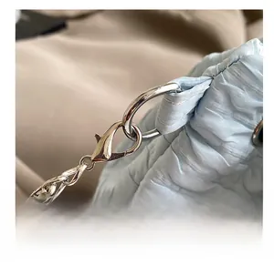 Détail du fermoir mousqueton argenté et de la chaîne sur un sac froncé bleu clair