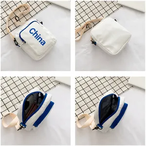 Detail of white square crossbody bag showing dual zip pockets and mesh interior divider