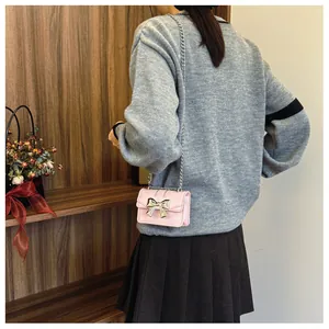 Detail of mini pink PU crossbody bag with metal bow and silver chain strap