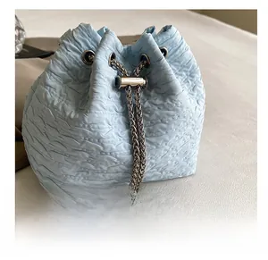 Détail du sac seau bleu clair avec cordon, chaîne argentée et décoration en perle