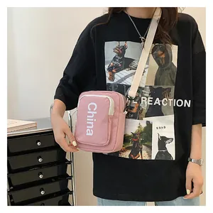 Pink canvas crossbody bag with white China lettering print and adjustable strap
