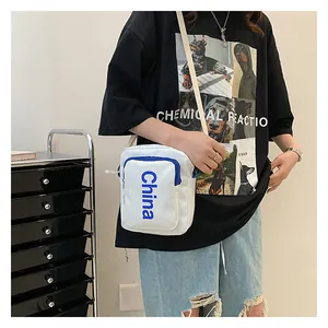 Close-up of white canvas crossbody bag featuring blue China text and contrast zipper