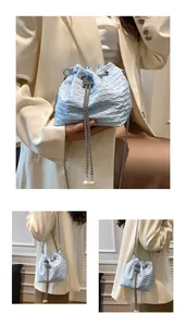 Gros plan sur un sac seau plissé bleu clair avec perles et bandoulière chaîne argent