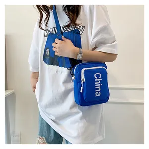 Detail of blue canvas crossbody bag with white China lettering and adjustable strap