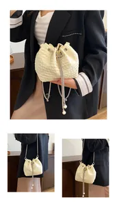 Détail du sac seau plissé beige avec cordon perlé et bandoulière chaîne argentée