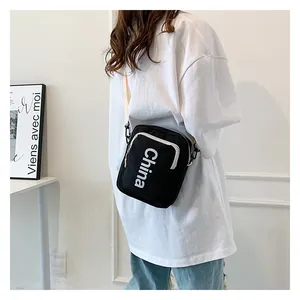Detail of black canvas crossbody bag with white China lettering and adjustable strap