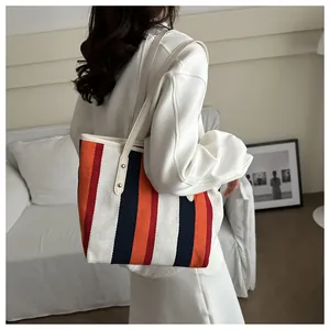 Detail of canvas tote bag with orange and navy stripes and leather handle rivets