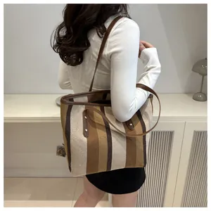 Detailed view of large canvas tote bag with brown vertical stripes and leather handle