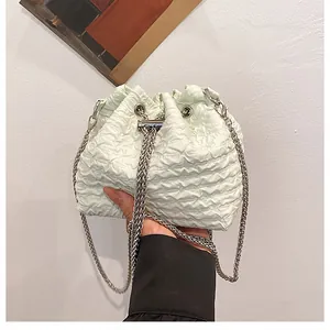 Détail du sac seau vert menthe avec texture plissée, cordon et bandoulière en chaîne