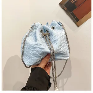 Détail du sac seau bleu clair montrant la texture plissée et la bandoulière chaîne