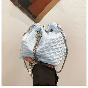 Détail du sac seau bleu clair plissé avec chaîne argentée et ornements en perles