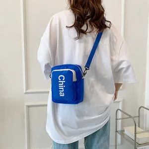 Blue canvas crossbody bag with white China lettering shown on a female model