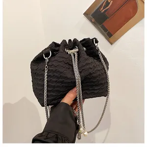 Détail du sac seau noir plissé avec bandoulière chaîne argentée et pendentif perle