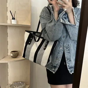 Chic black and white striped canvas tote bag with leather handles shown in use