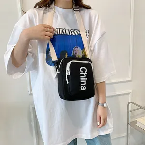 Black canvas crossbody bag with white China text and adjustable cream shoulder strap