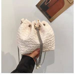 Détail du sac seau blanc avec plis, chaîne argentée et perle élégante décorative