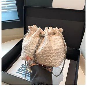 Vue détaillée du sac seau plissé beige avec chaîne argentée et détail perle