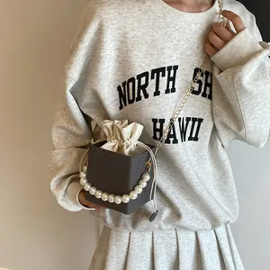 Striped box bucket bag with pearl handle and gold chain strap shown on a model