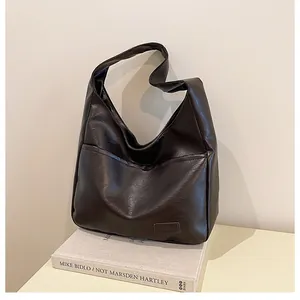 Detail of deep brown faux leather tote bag showing textured surface and side pocket