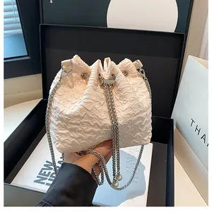 Détail du sac seau plissé blanc cassé avec chaîne argentée et glands de perles