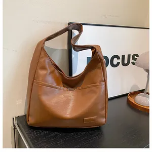 Detail of caramel hobo bag featuring smooth leather texture and spacious front pocket