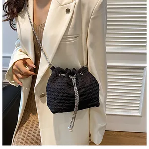 Détail d'un sac seau noir plissé avec cordon et bandoulière en chaîne argentée