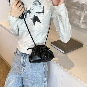 Sac à bandoulière plissé noir tendance style nuage avec fine sangle sur fond minimaliste
