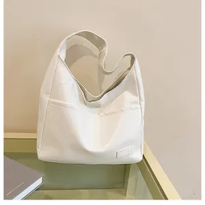 Detail of the litchi grain leather texture and magnetic buckle on the ivory tote bag