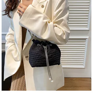 Vue détaillée du sac seau noir plissé avec bandoulière chaîne argentée et cordon de serrage